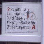 Apotheken-Schild: Hier gibt es die original Melsunger Gesäß-Salbe für Fahrradfahrer.